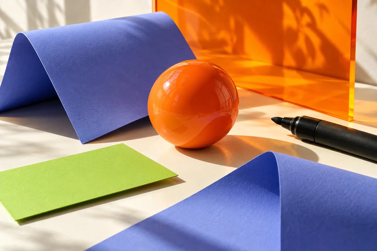 Orange and periwinkle shapes on a creative desk, illustrating a campaign taking shape